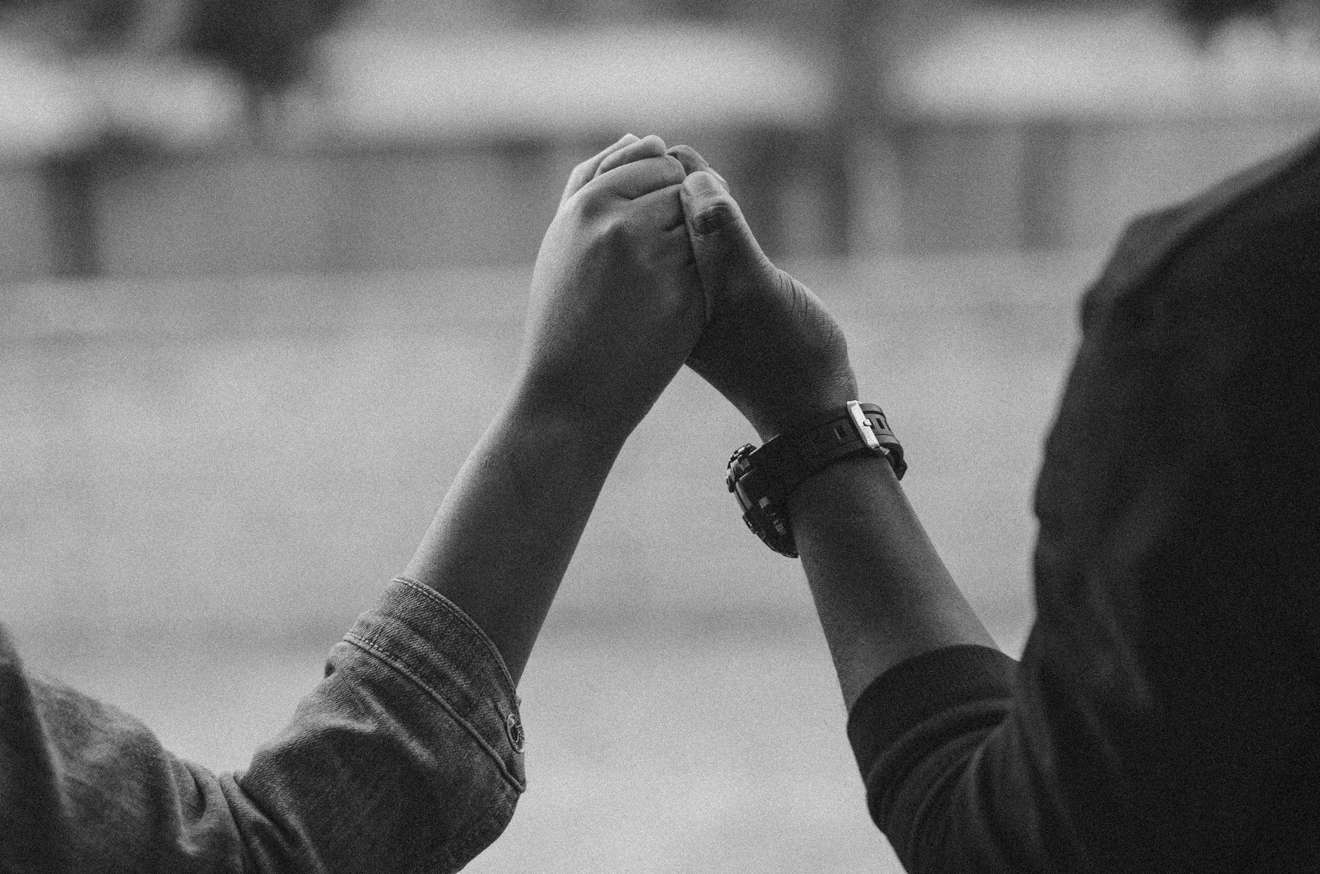 A close-up of a couple holding hands, signifying love and connection in a black and white setting.